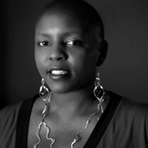 A woman wearing earrings and a necklace smiles at the camera