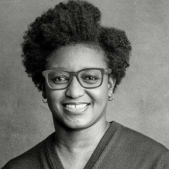 Nekisa Cooper headshot, a woman with short hair and thick frames smiling at the camera