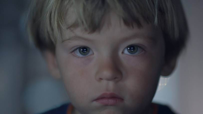 Still from Users. A young boy's face in an extreme close-up looks directly at the viewer.