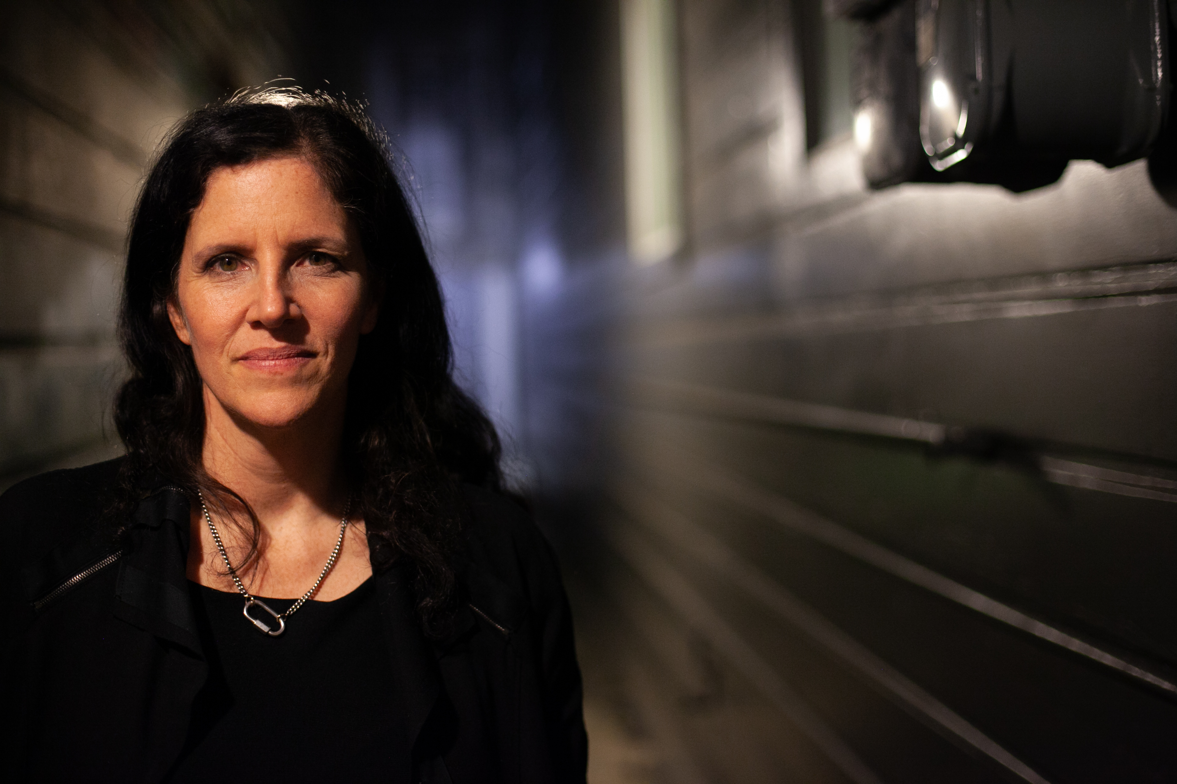 Laura Poitras stands next to a wall and smiles