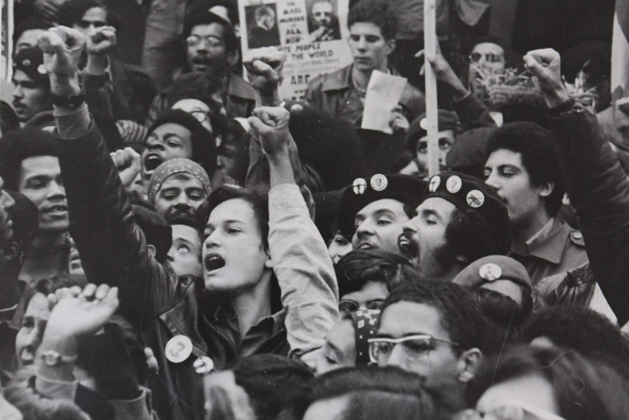 A group of people yell and raise fists at a protest