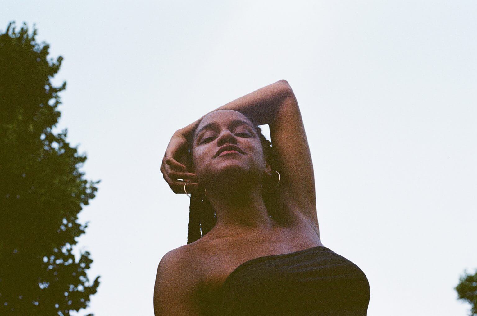 Low angle shot of Beba, placing her arm behind her head and wearing a black top