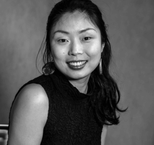 Headshot of a woman with a pony tail, a short sleeve shirt and smiling at the camera