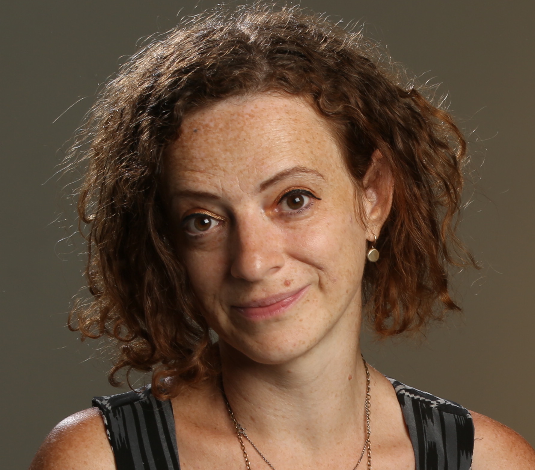 Irene Lusztig headshot. A white woman with chin-length curly hair and a black dress smiles for the camera.