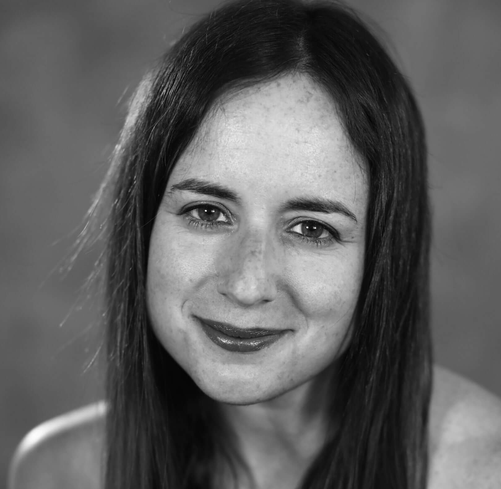 Maite Alberdi slightly smiles. She has long dark hair and wears a dark sleeveless top. Black and white portrait.