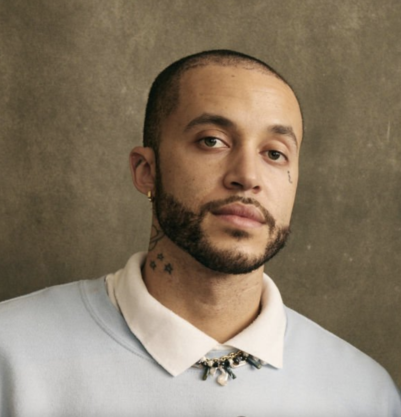 Headshot of richie reseda wearing a blue sweatshirt and white collared shirt against a gray backdrop.