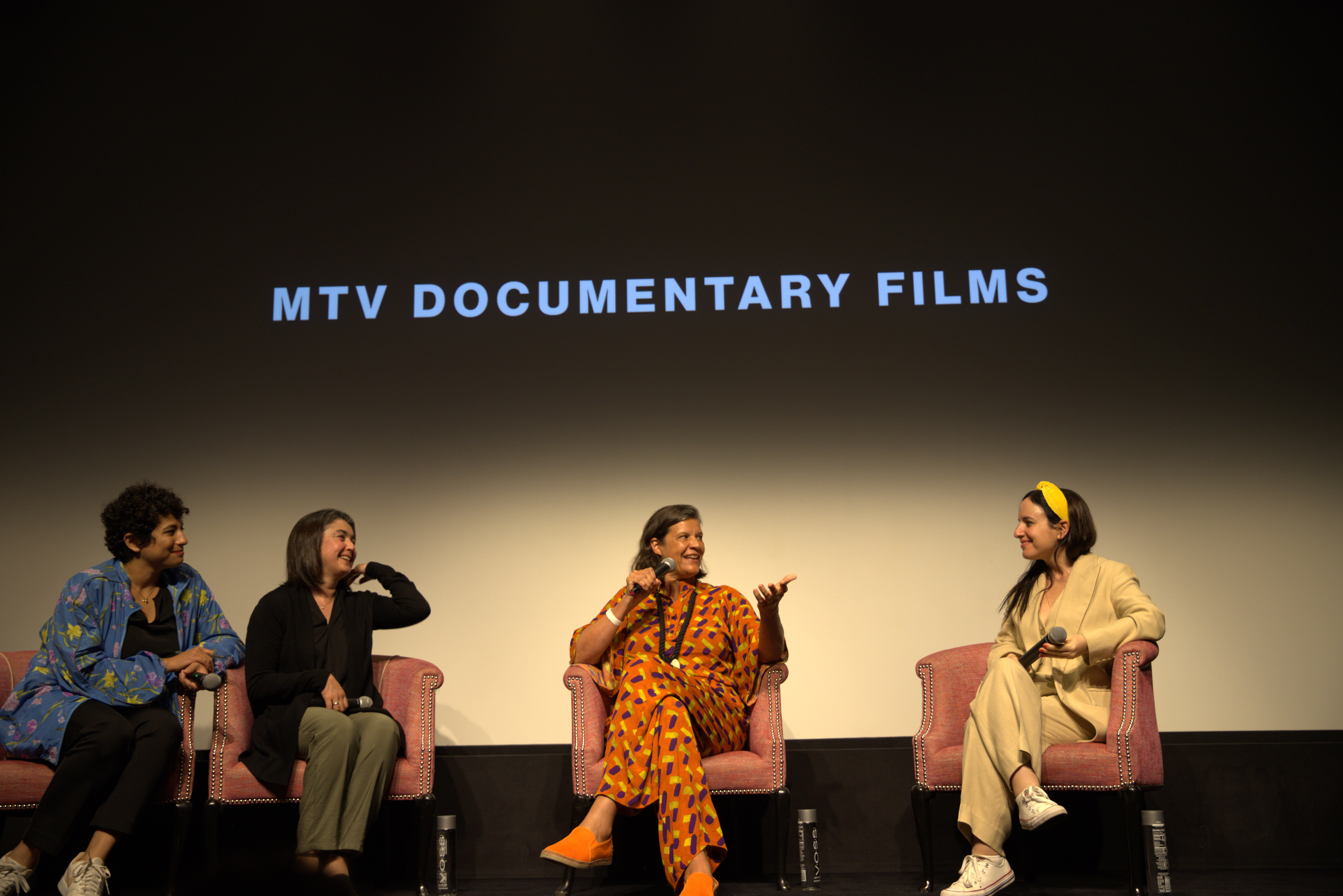 Q&A with filmmaker Maite Alberdi. From left to right: Translator, film participant Pauli, Moderator Kirsten Johnson, and filmmaker Maite Alberdi. They are all sitting in front of a screen.