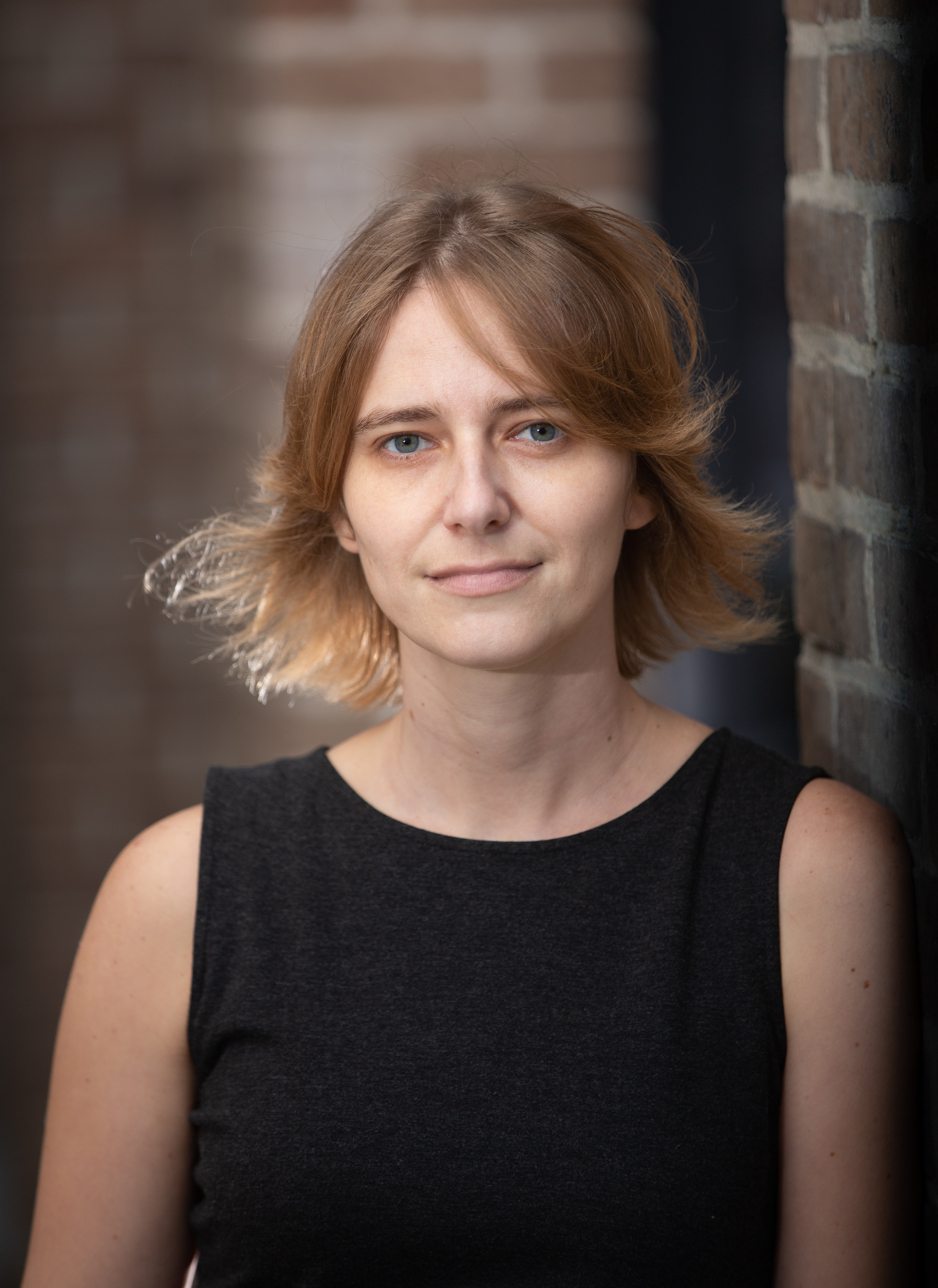 Portrait of Emily Faye Ratner, she looks at the camera, has short hair and sleeveless shirt. 