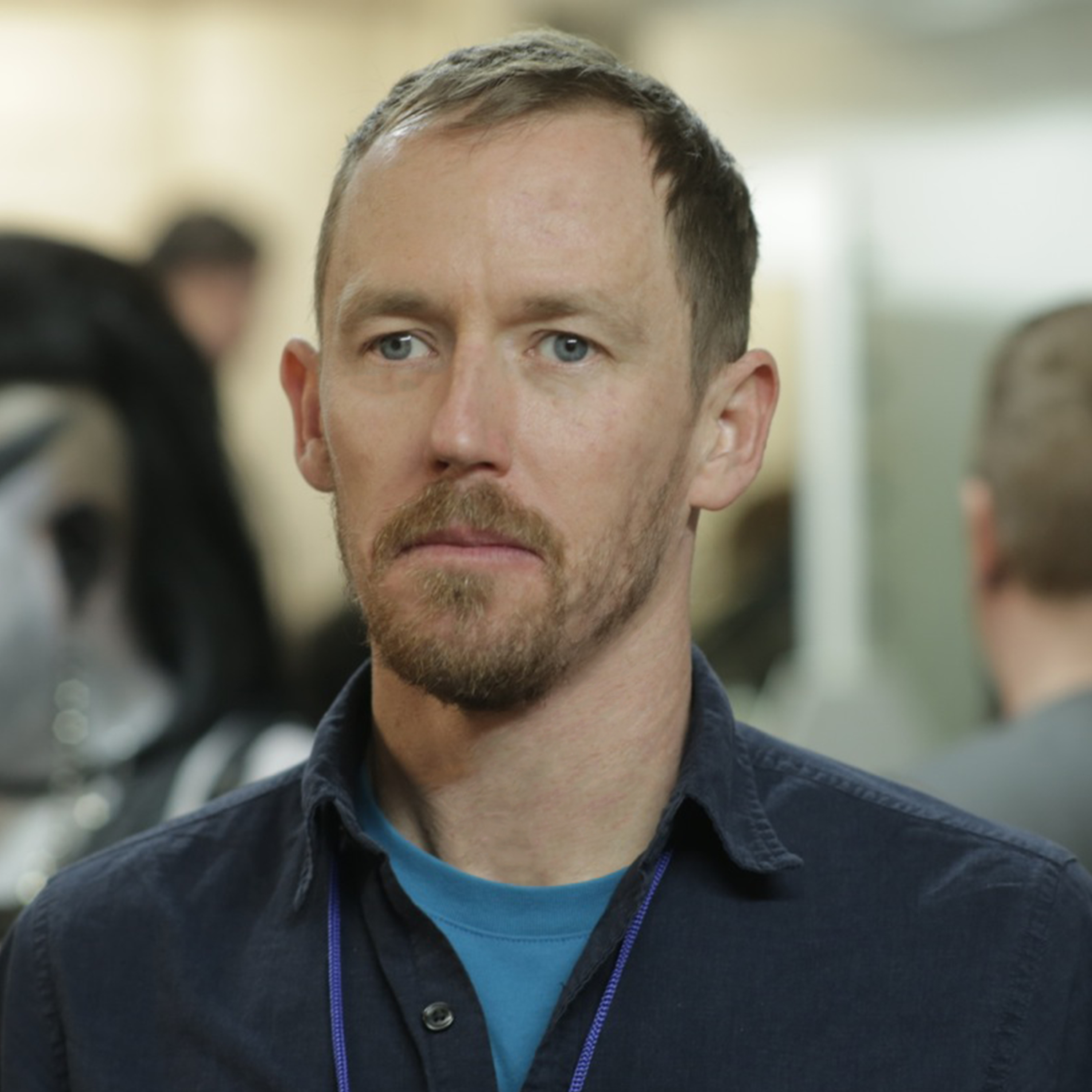 Portrait of a man with short hair and short beard, wearing a short and a t-shirt underneath