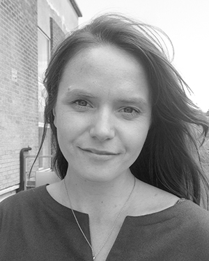 A black and white portrait of a woman looking into the camera and smiling.