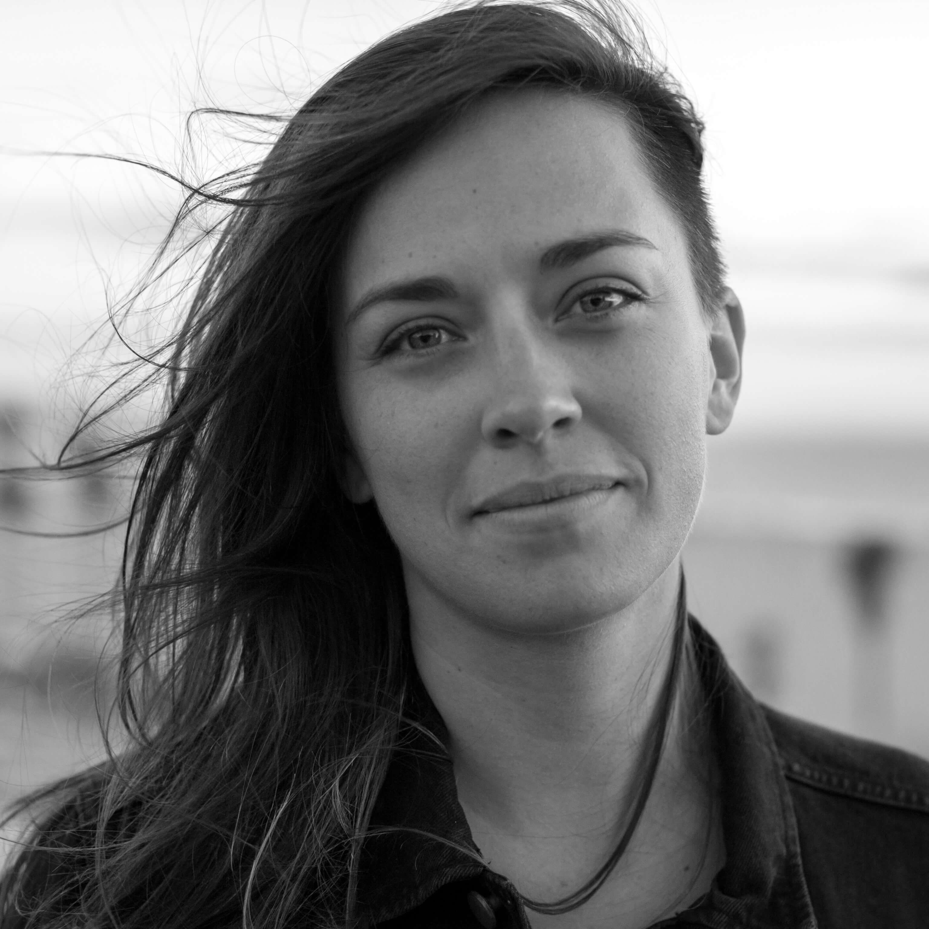 Alexandria Bombach slightly smiling, her hair is flowing in the wind. Black and white portrait.