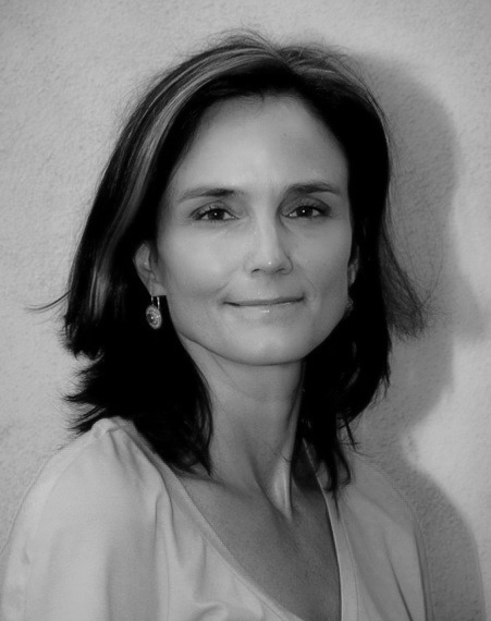 Portrait of Gay Dillingham, she smiles slightly at the camera, has medium length hair, a v neck blouse, and earrings.