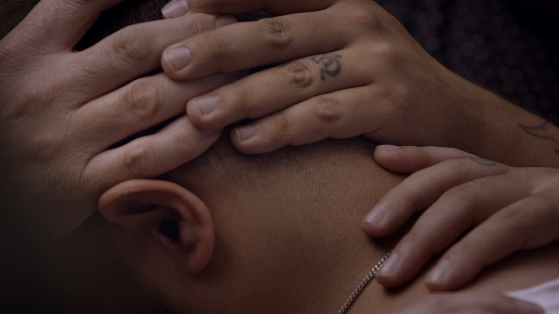 Multiple individual hands are laid on top of a person's head, as in a religious ceremony 'laying of hands' - a still from the film Pray Away