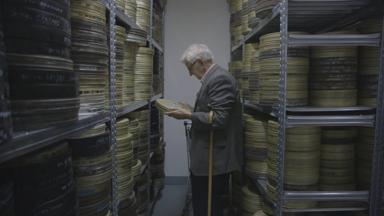 Still from Scenes From The Labudović Reels. Stevan Labudović in the archives of the Yugoslav Newsreels surrounded by reels of films he shot during the Algerian Liberation War.