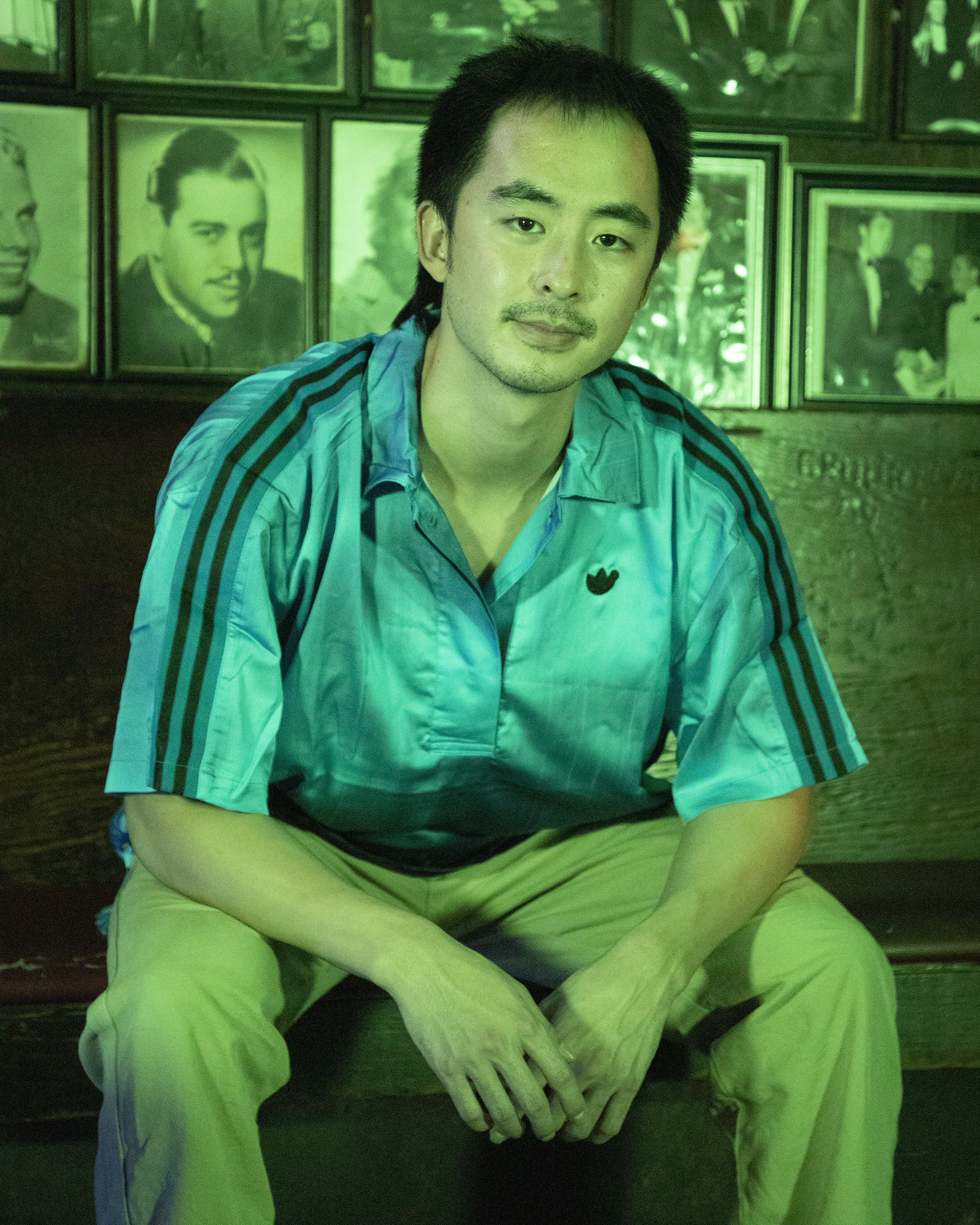 A photo of Patrick G. Lee on a bench under green lighting.