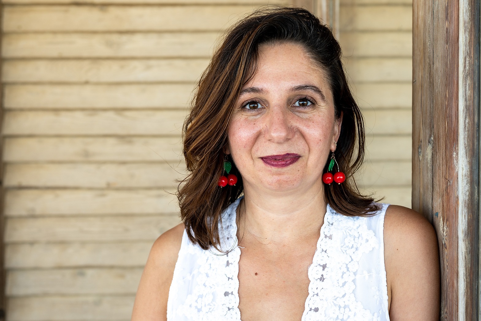 A portrait of May Odeh in front of a clapboard wall.