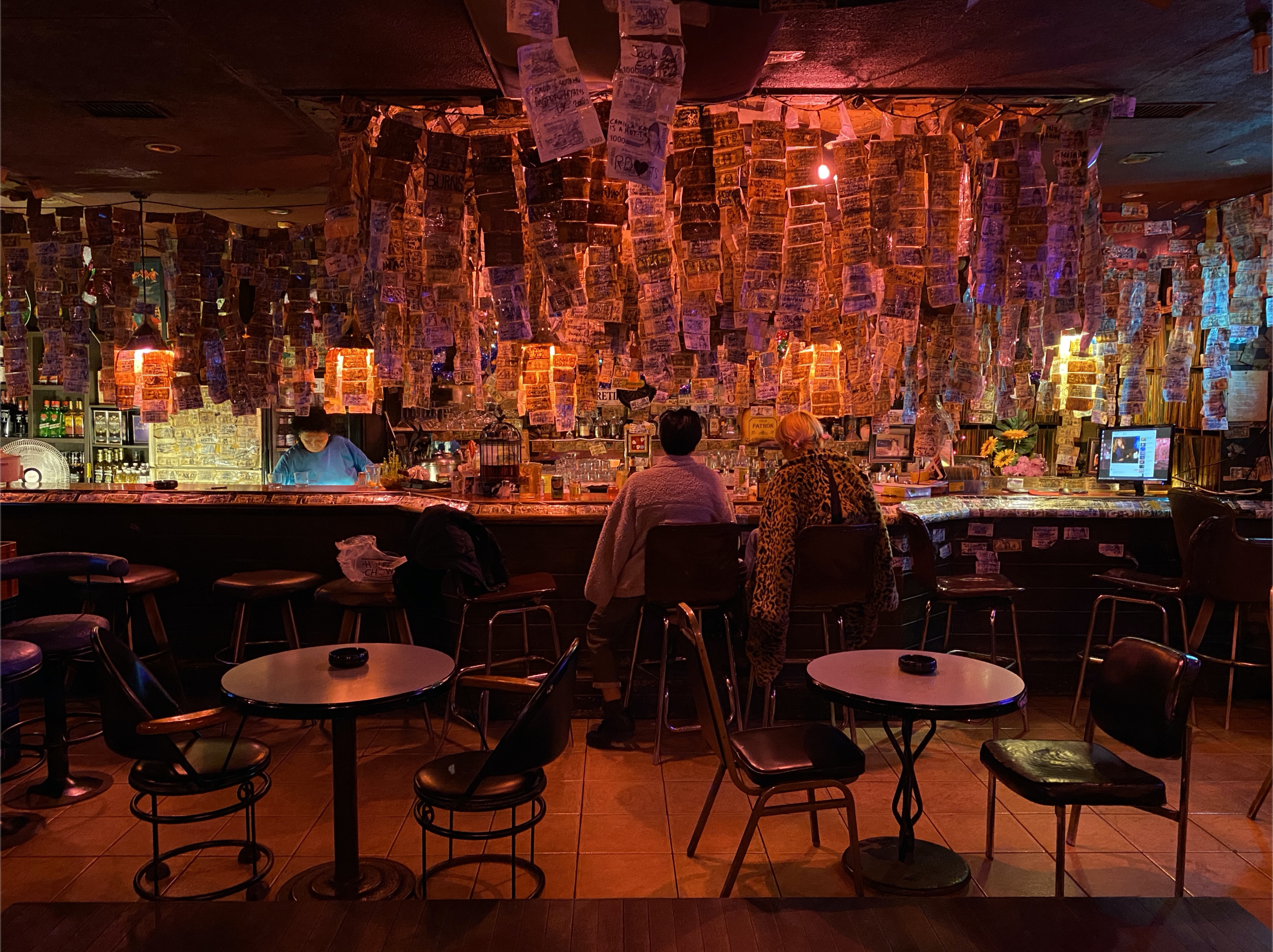 A photo of two people sitting at a bar in an empty nightclub.