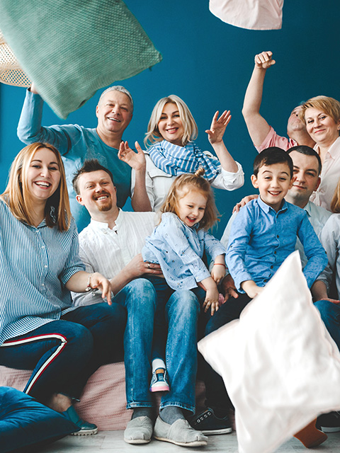 480x640 grandparents parents and their little children sit together on the bed in blue room