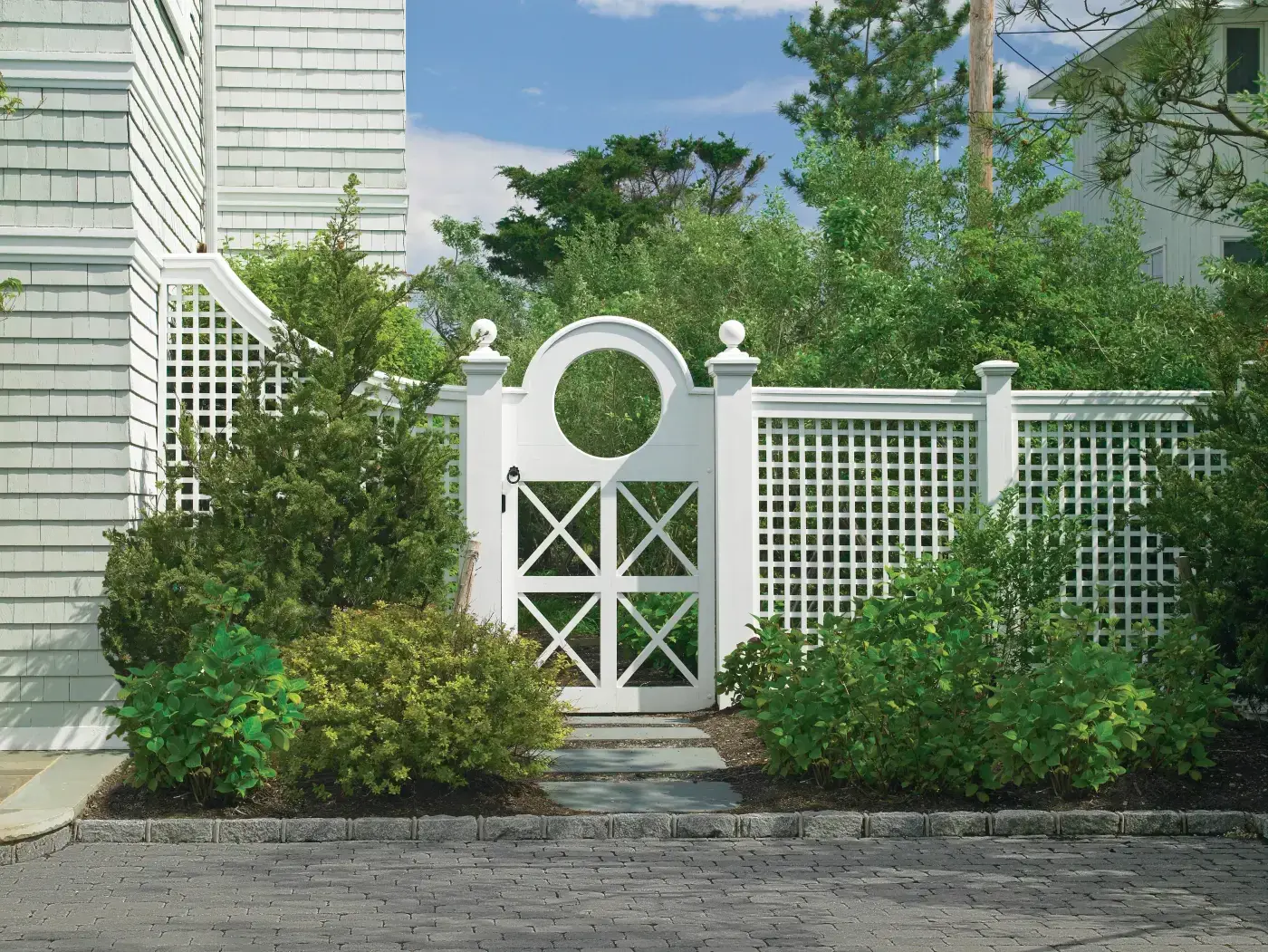 There are countless way that Walpole Outdoors helps our clients express their creative ideas with regard to fences and outdoor structures. Here, the magnificent Porthole gate with circular cutout and crisscross panels is a distinctive complement to the horizontal/vertical lattice panels.