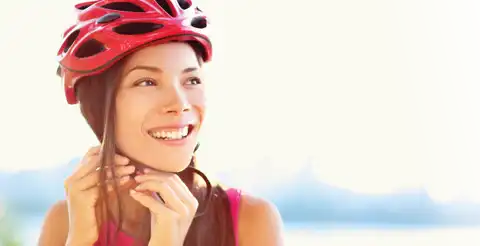 Woman smiling, buckling her helmet as she gets ready for a bike ride.