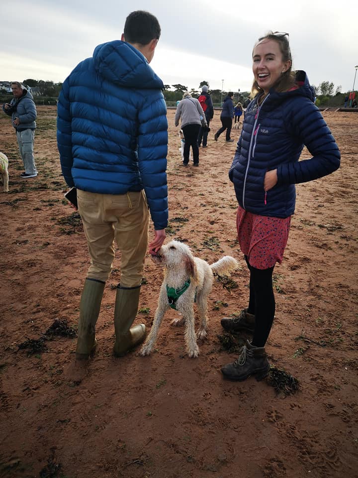 two people and a labradoodle on beach