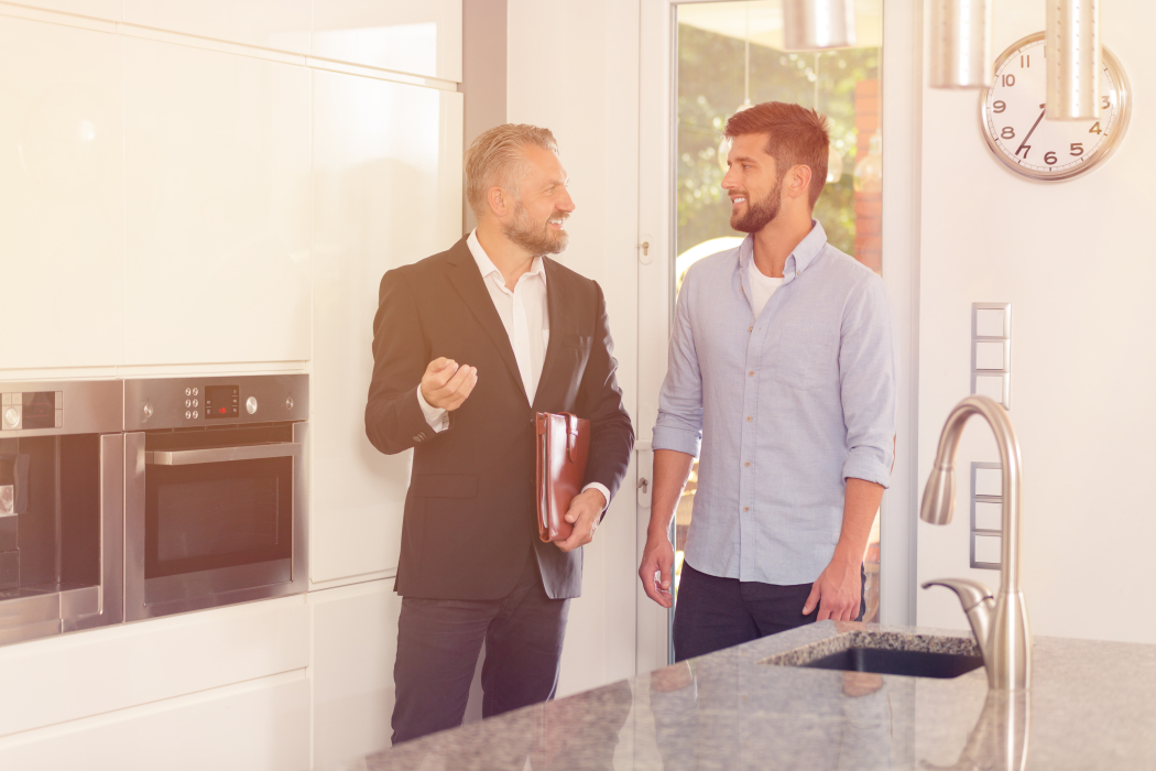 stock-photo-real-estate-consultant-talking-about-house-while-inspecting-the-kitchen-with-smiling-customer-750835114