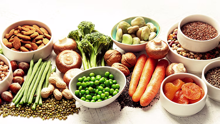 Broccoli, peas, carrots, chickpeas. Lentils, buckwheat, peanuts and dries apricots places on a white wooden table.