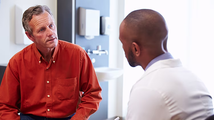A man in orange shirt talking to doctor.