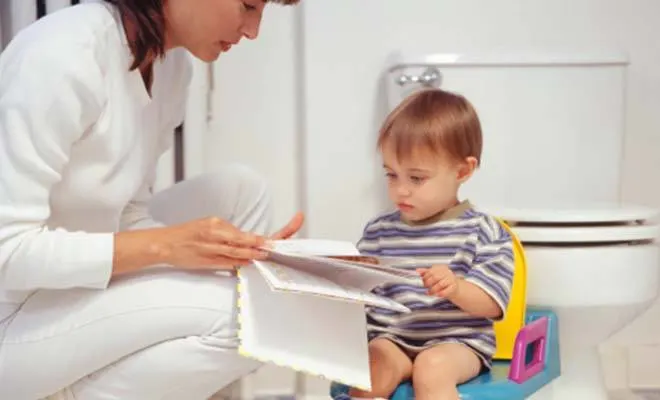 Mom reading child a book while sitting on potty training seat