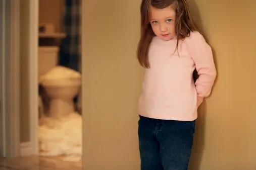 Little girl looking guilty against wall outside of overflowing bathroom