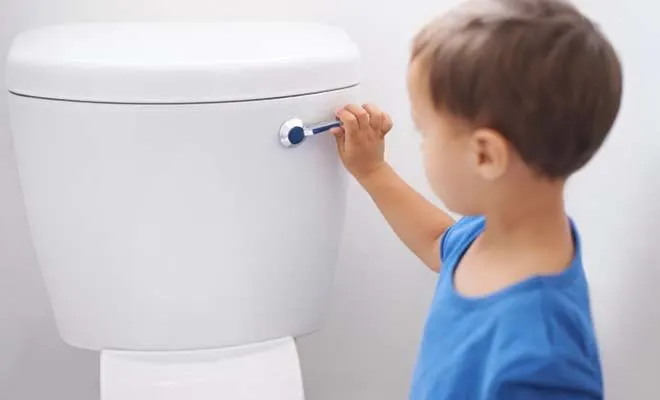 Boy standing up flushing toilet