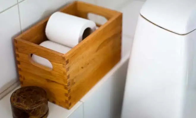 Un boîtier de bois contient des rouleaux de papier hygiénique dans la salle de bain.