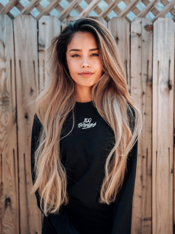 Valkyrae posing stoicly in front of wooden fence