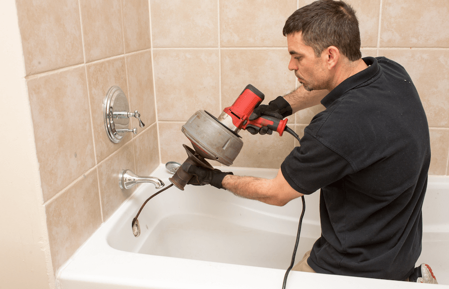 A plumber clearing a clogged drain in the bathroom