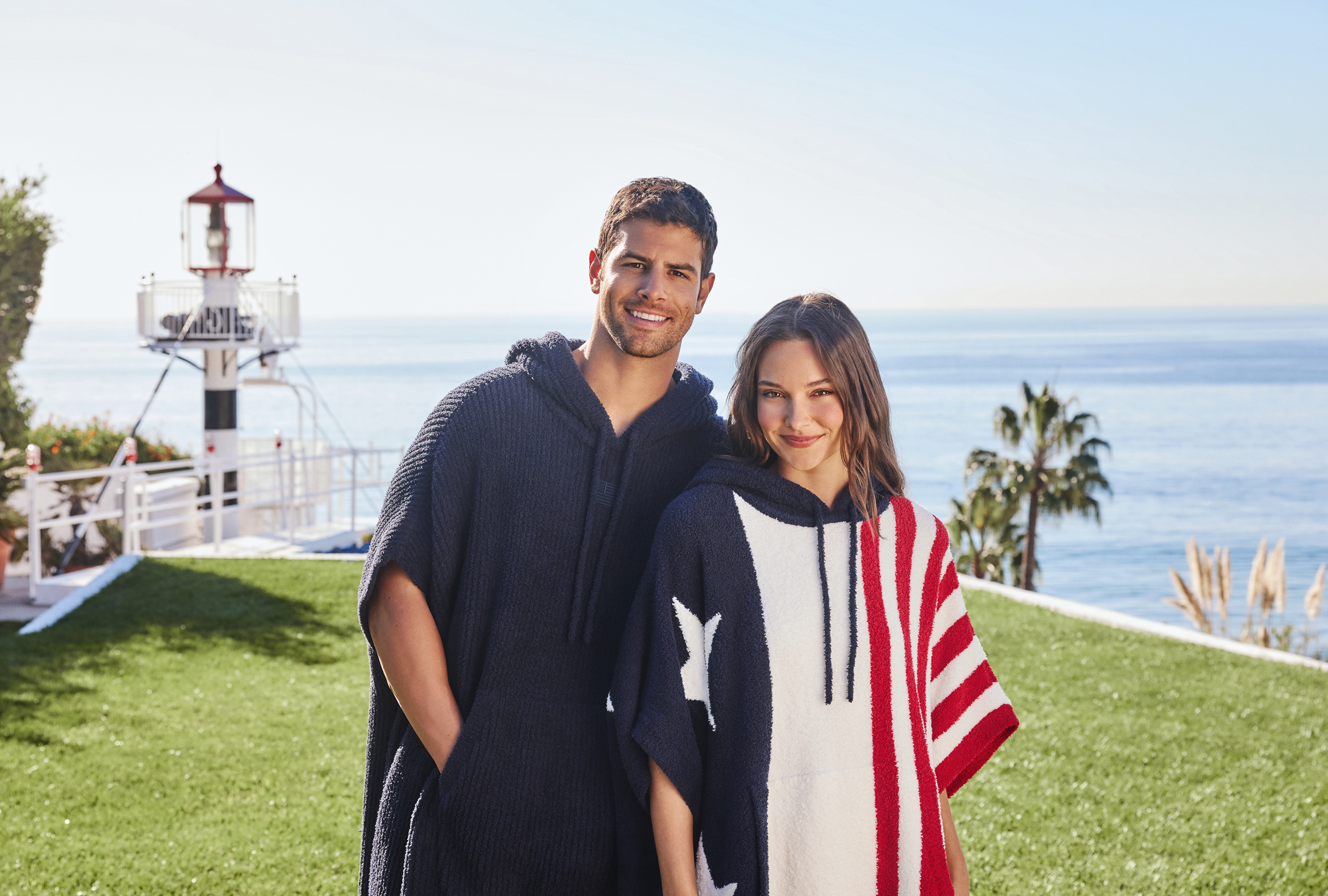 A man and woman in red, white and blue "Cozys" on an ocean-front lawn.