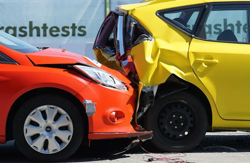 A rear end car accident between a red and yellow car.