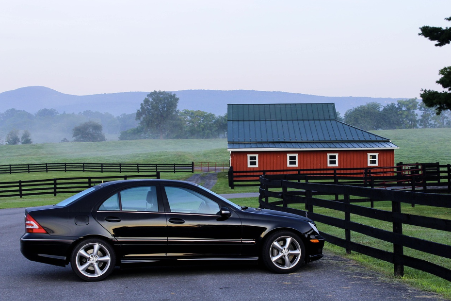 Black sedan parked on a rural driveway near a red barn, used in a Quashed review of Tower Insurance.