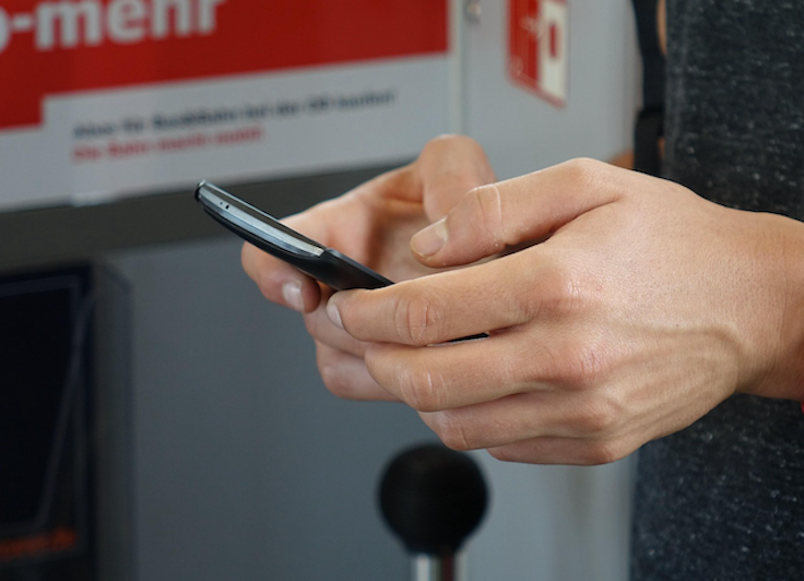 A person using a smartphone to compare car insurance quotes online, representing the step of arranging cover before collecting a vehicle from a New Zealand car dealer.