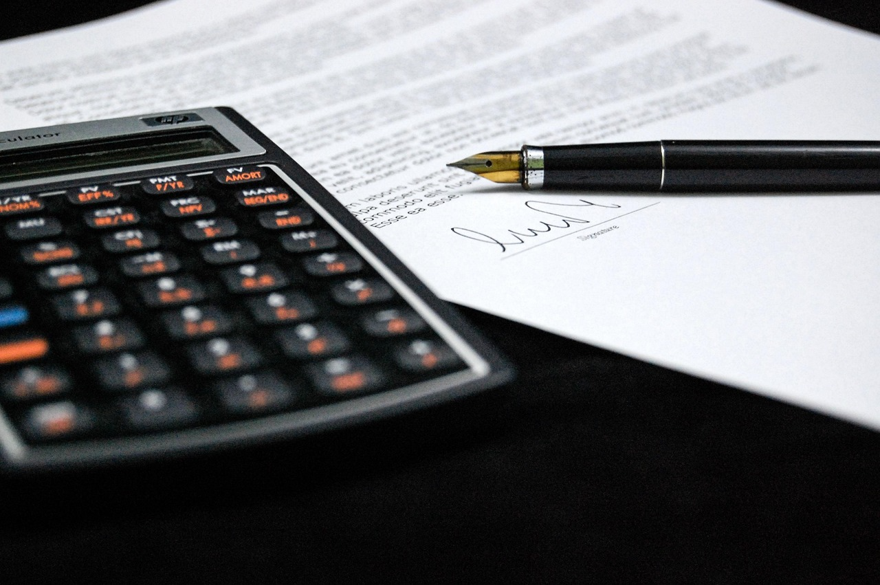 A calculator and pen resting on a document; used for calculating 2026 car ownership costs and the $367 average annual savings found via Quashed.