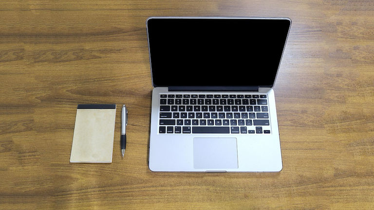 A laptop and notebook on a desk, representing how Kiwis use the Quashed Market Scan in 2026 to compare FMG insurance prices against 10+ other providers.