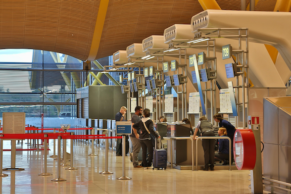 Travelers at an airport check-in counter, representing the final moment to ensure travel insurance is active before departing New Zealand, featured in this Quashed 2026 article.