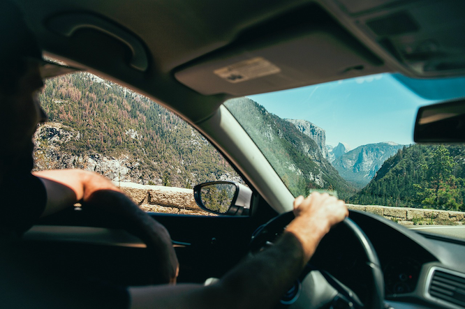 A Kiwi driver with their hand covering their vehicle licence label and WoF sticker on a car windscreen, representing how expired registration or Warrant of Fitness can affect insurance claims in New Zealand.