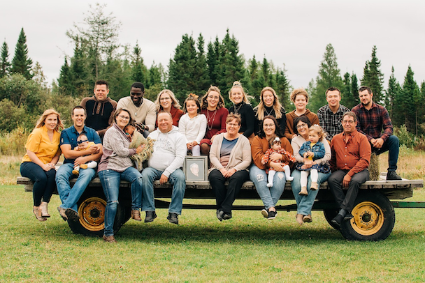 A large Kiwi family gathered on a farm trailer, reflecting FMG’s community focus and mutual structure as reviewed by Quashed in 2026.