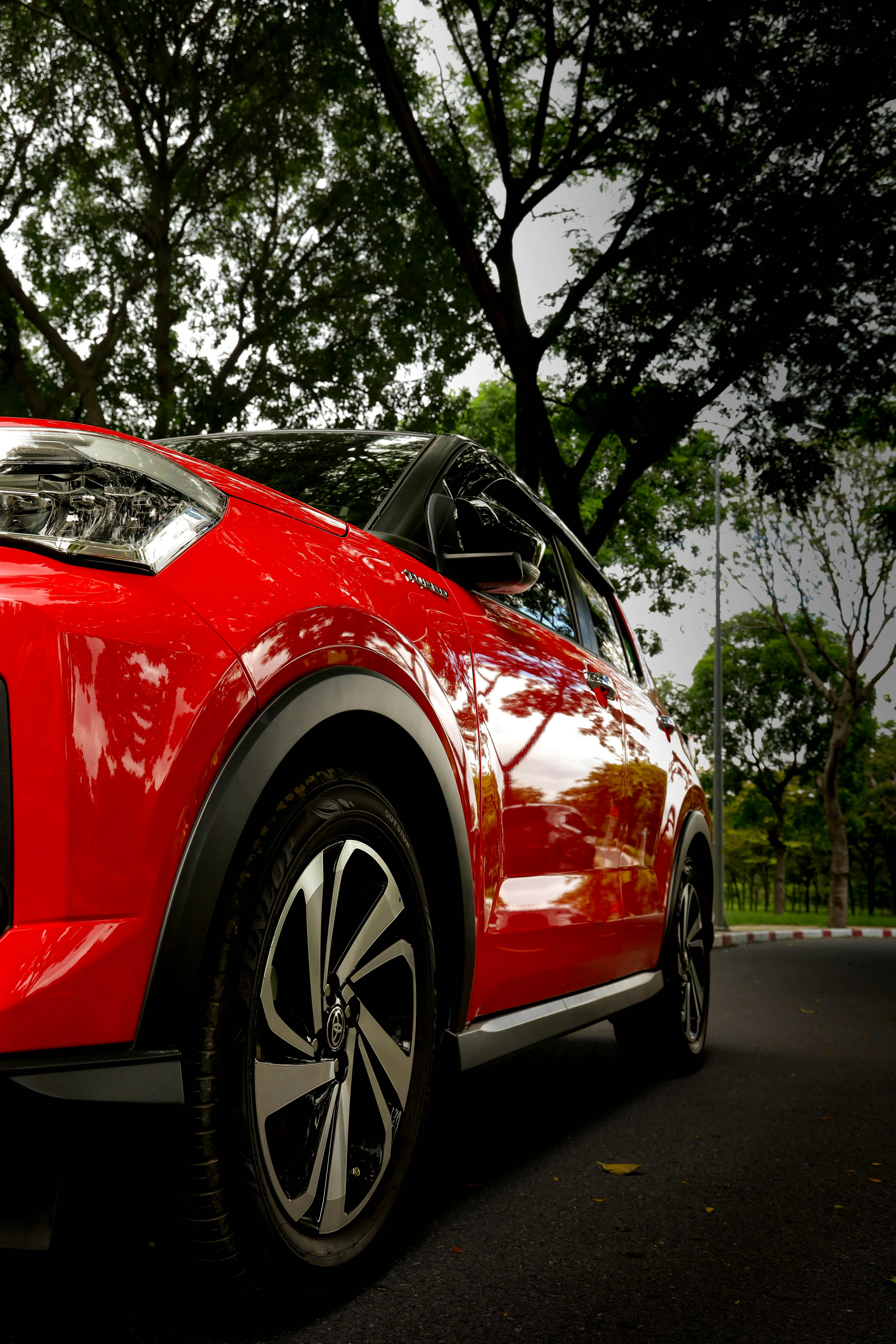 Low-angle view of a red Toyota Yaris Cross SUV with a black bi-tone roof and turbine-style alloy wheels.