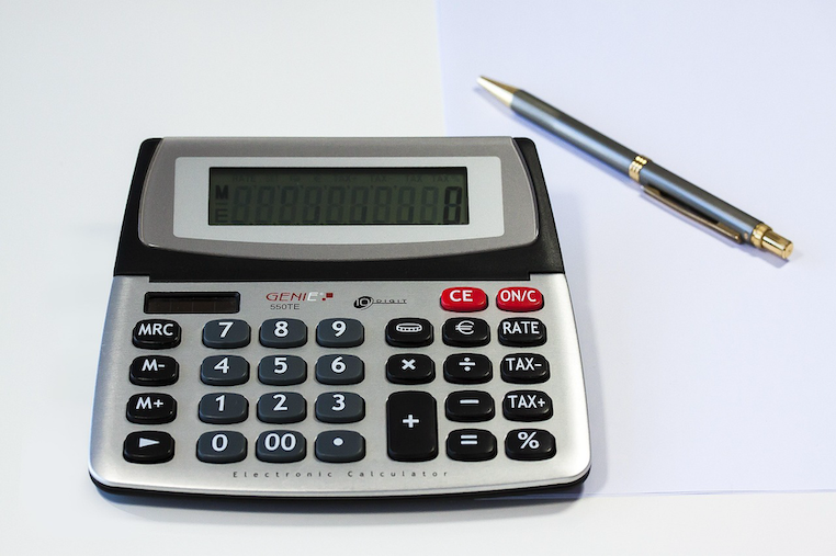 A calculator and pen on a desk.