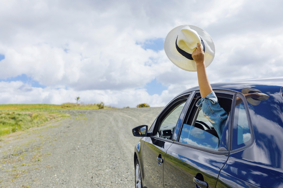 Person waving a hat from a car window on a gravel road — Quashed image for Tower Insurance article.