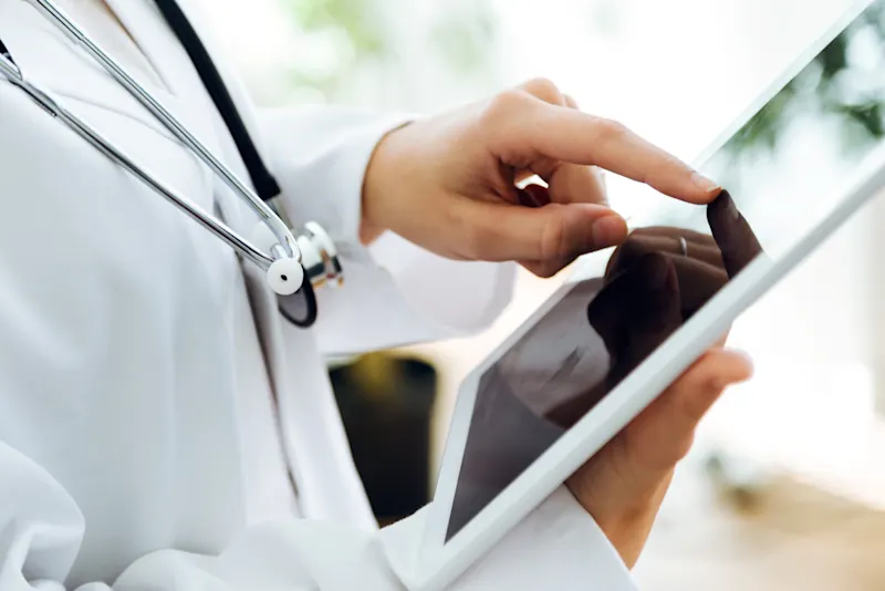 A doctor using a tablet to complete a medical assessment.