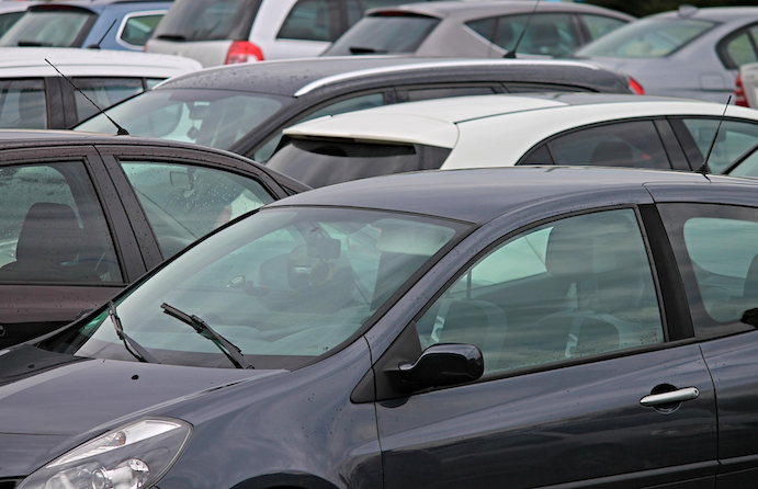 A busy car park filled with rows of vehicles, representing the various parking options at Auckland Airport and how choosing the right one can reduce a driver's exposure to weather, theft, and accidental damage.