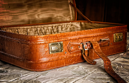 An open vintage leather suitcase on a patterned surface, featured in this 2026 Quashed guide. 