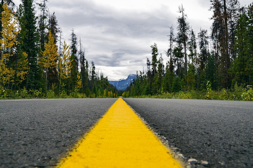 A paved road with a solid yellow line in the center leading toward mountains in the distance, featured in this 2026 Quashed article.